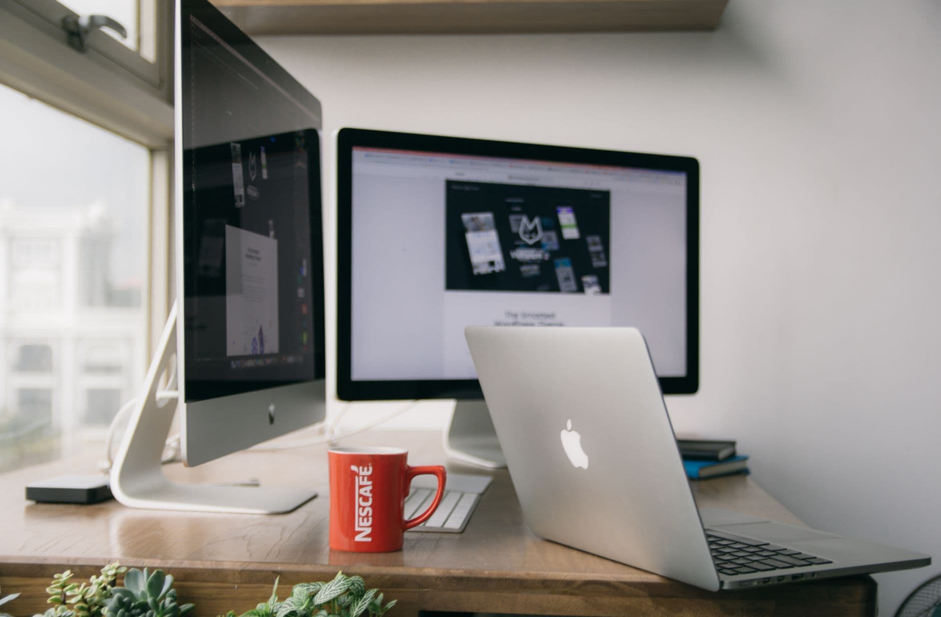 A bright modern office setup with computers and a mug on a desk.