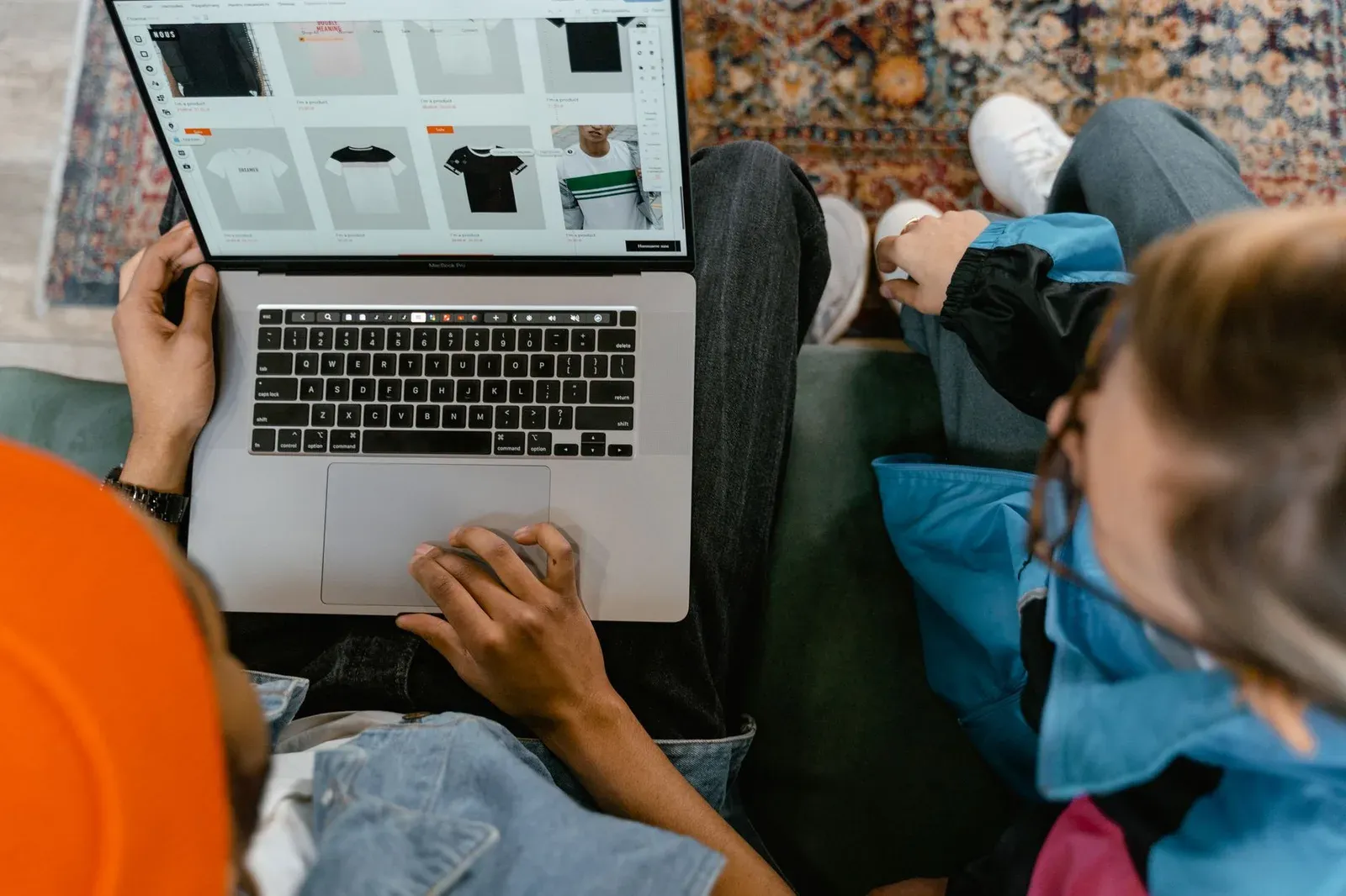 Two people browsing online clothing store on a laptop from above.